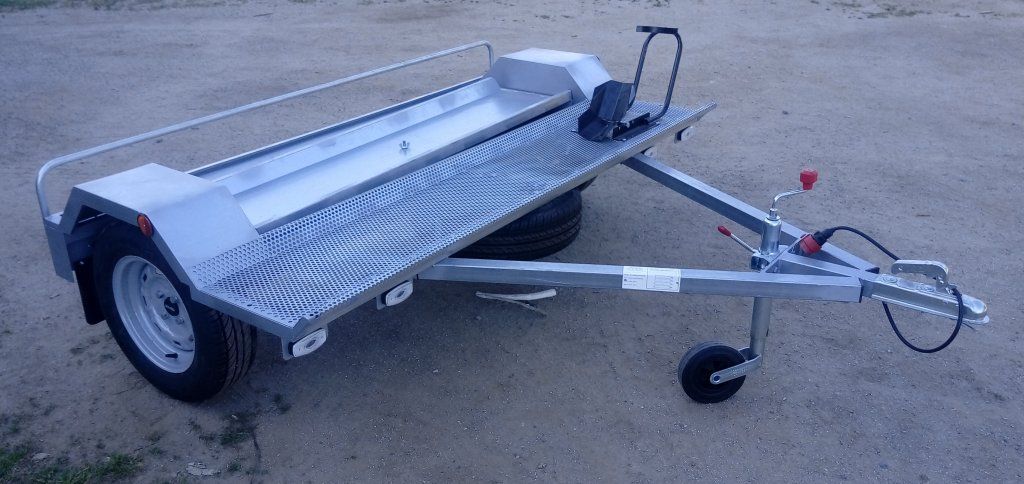 Un remolque de motocicleta está estacionado en un camino de tierra.