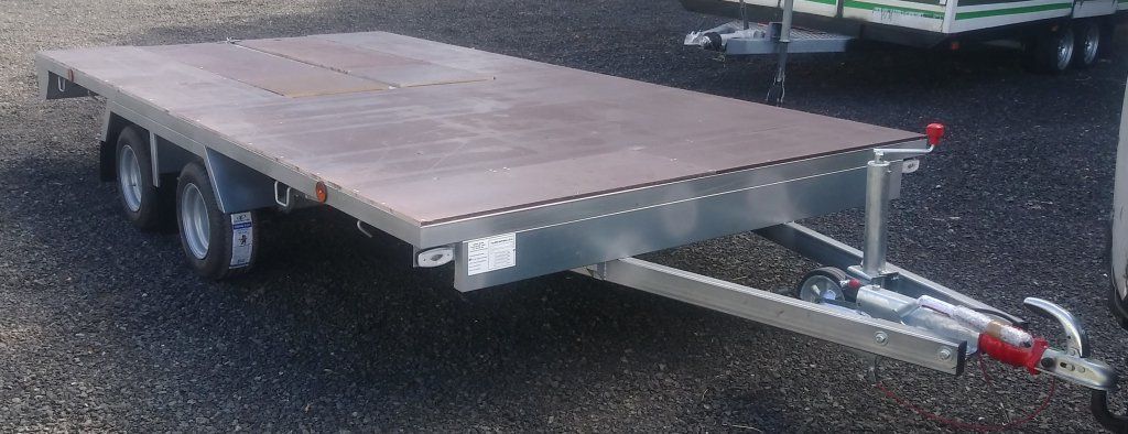 Un remolque de plataforma está estacionado en un camino de grava