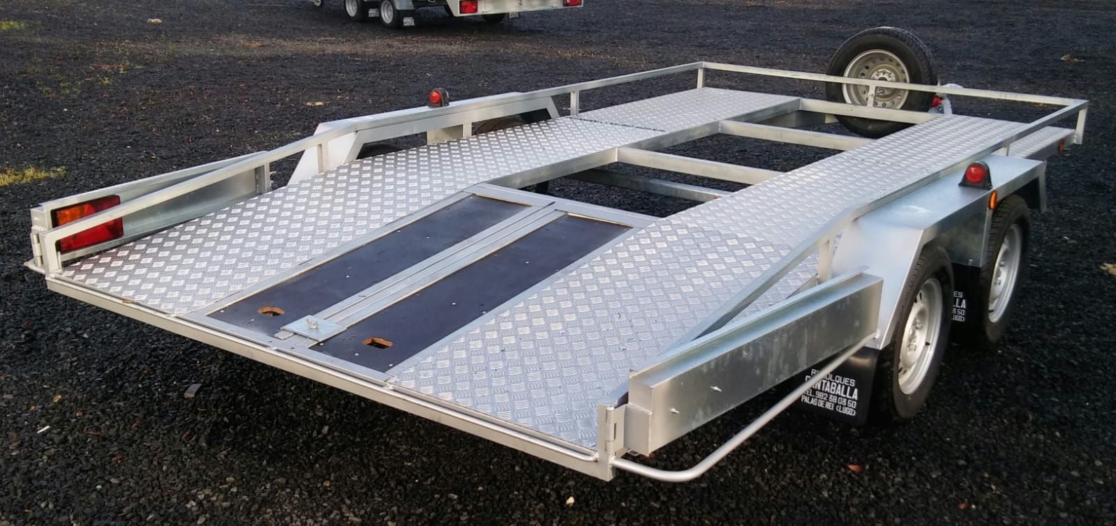 Un remolque plateado con una franja negra en el costado