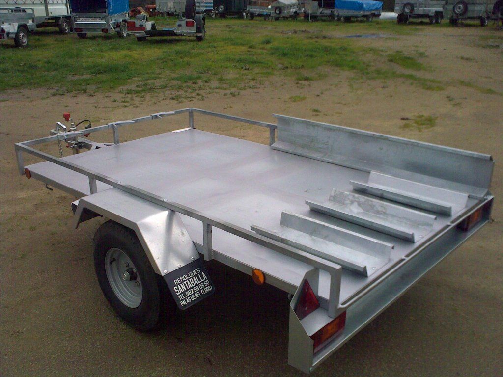 Un remolque de motocicleta está estacionado en un camino de tierra