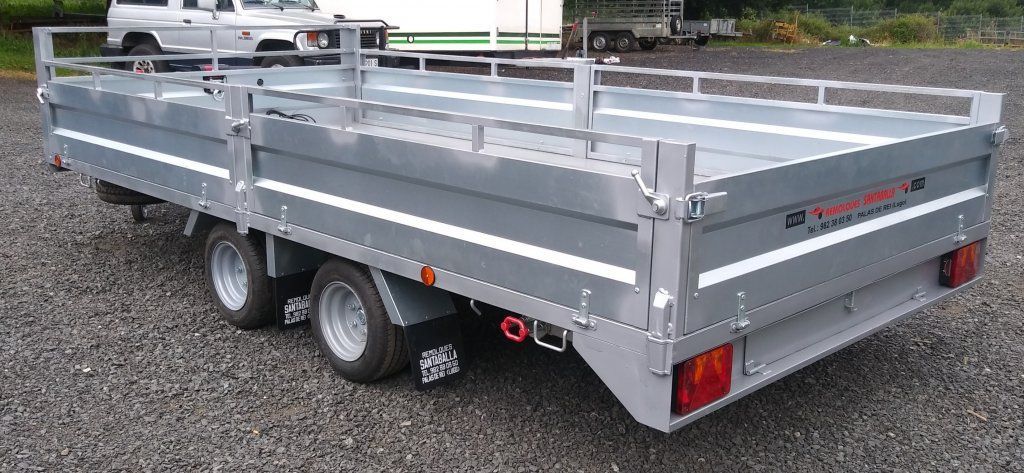 Un remolque gris está estacionado en un lote de grava.