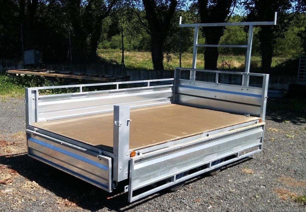 Una caja de metal con un fondo de madera se encuentra en un área de grava.