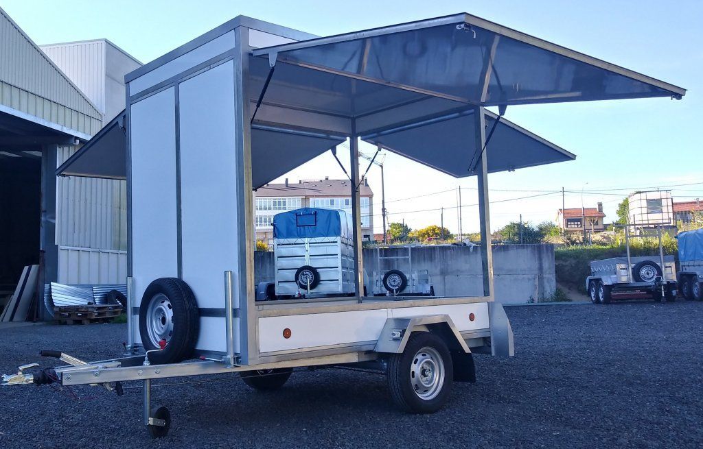 Un remolque blanco con toldo está estacionado en un lote de grava.