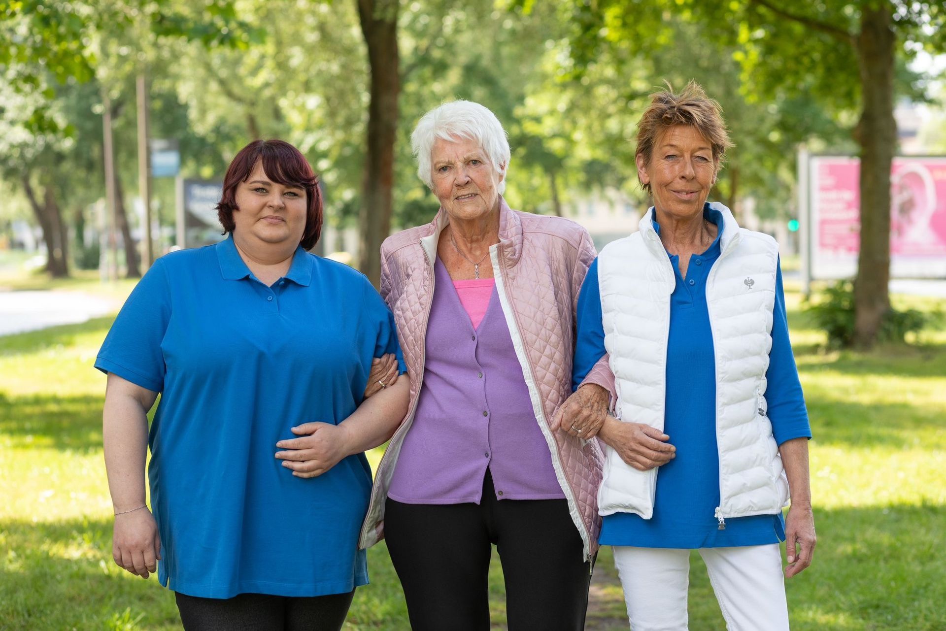 Eine Krankenschwester gibt einer älteren Frau im Rollstuhl einen Apfel.