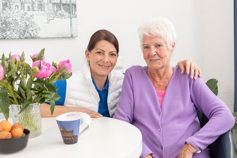 Eine Krankenschwester hält in einem Pflegeheim die Hand eines älteren Mannes.
