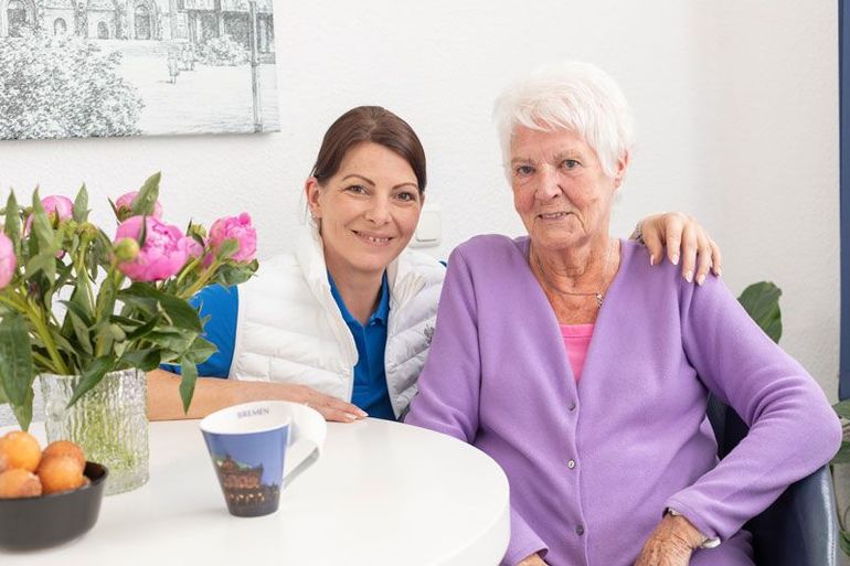 Eine Krankenschwester hält in einem Pflegeheim die Hand eines älteren Mannes.