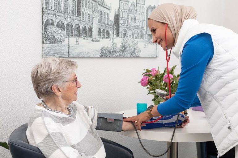 Eine Krankenschwester hilft einer älteren Frau im Rollstuhl.