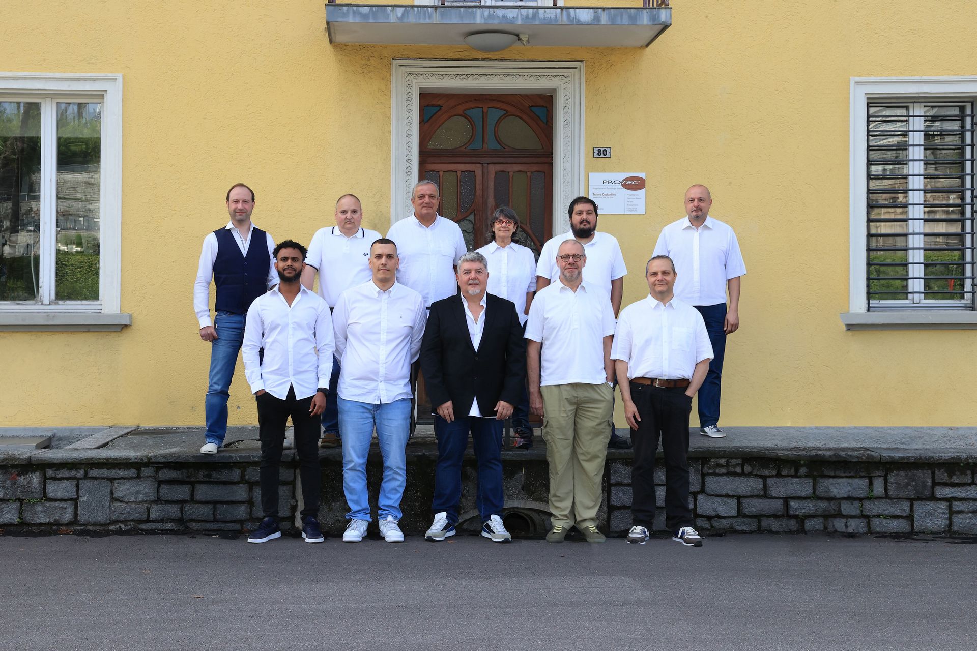 Un gruppo di uomini posa per una foto davanti a un edificio giallo.