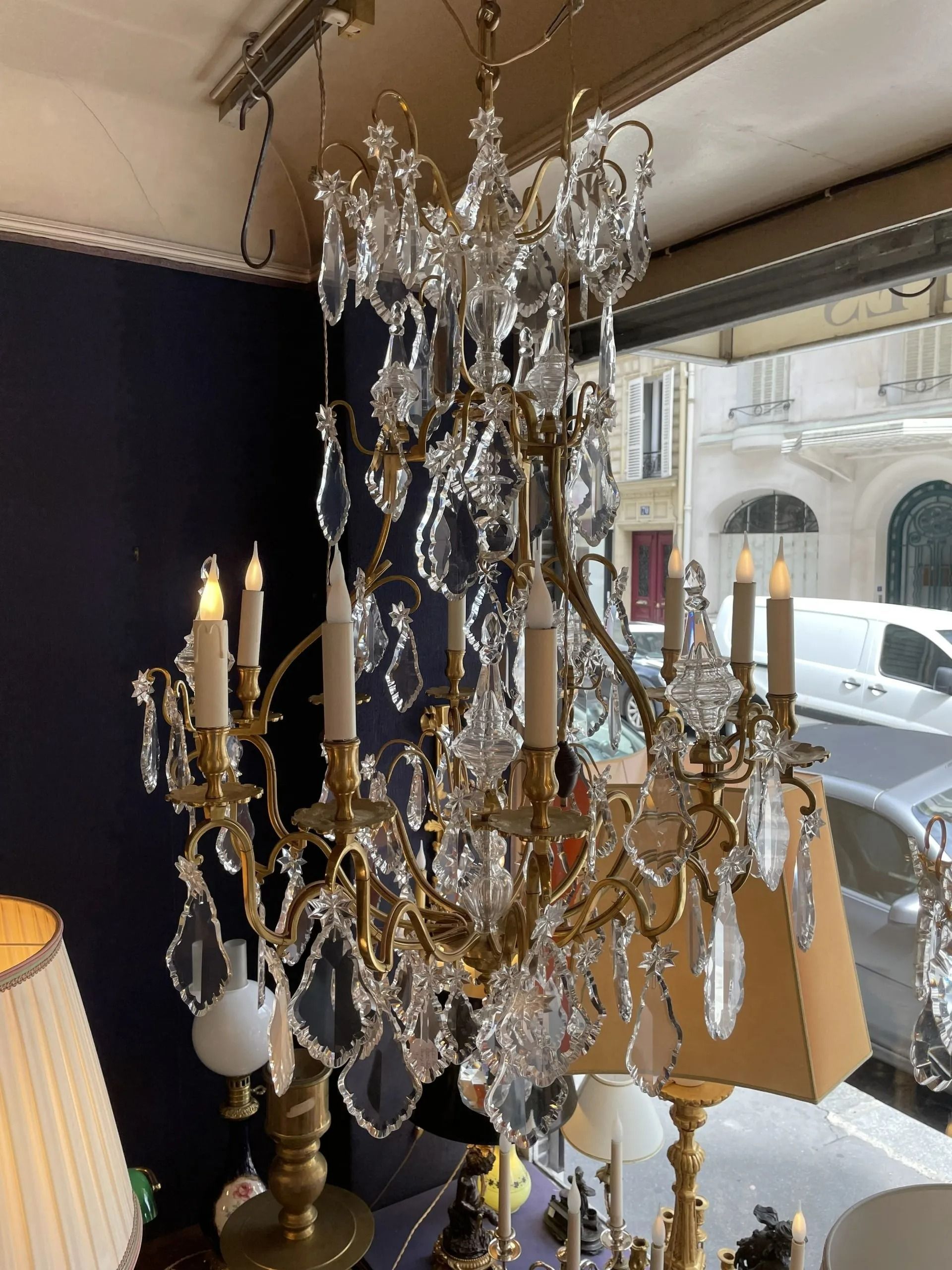 Lustre en cristal et lampes candélabres près d'une fenêtre dans une pièce sombre et élégante.