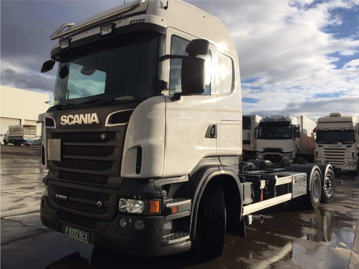 Un camión semirremolque Scania blanco está estacionado en un estacionamiento.