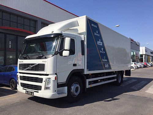 Un camión blanco está estacionado frente a un edificio.