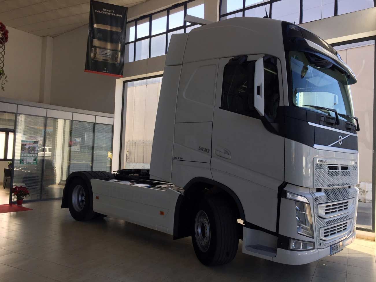 Un camión semirremolque blanco está estacionado en una sala de exposición.