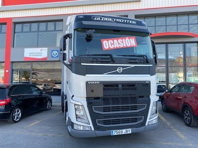 Un camión Volvo está estacionado en un estacionamiento frente a un edificio.