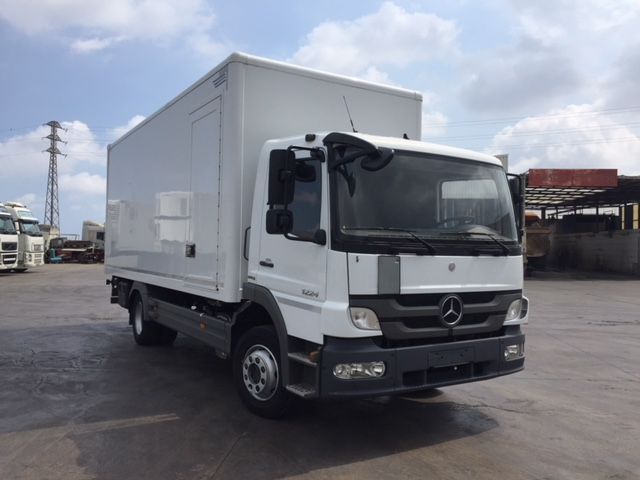 Una camioneta Mercedes blanca está estacionada en un estacionamiento.