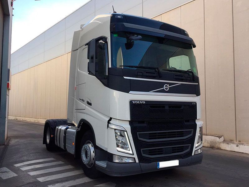 Un camión semirremolque Volvo blanco está estacionado frente a un edificio.