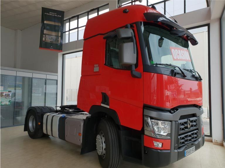 Un camión semirremolque rojo está estacionado en una sala de exposición.