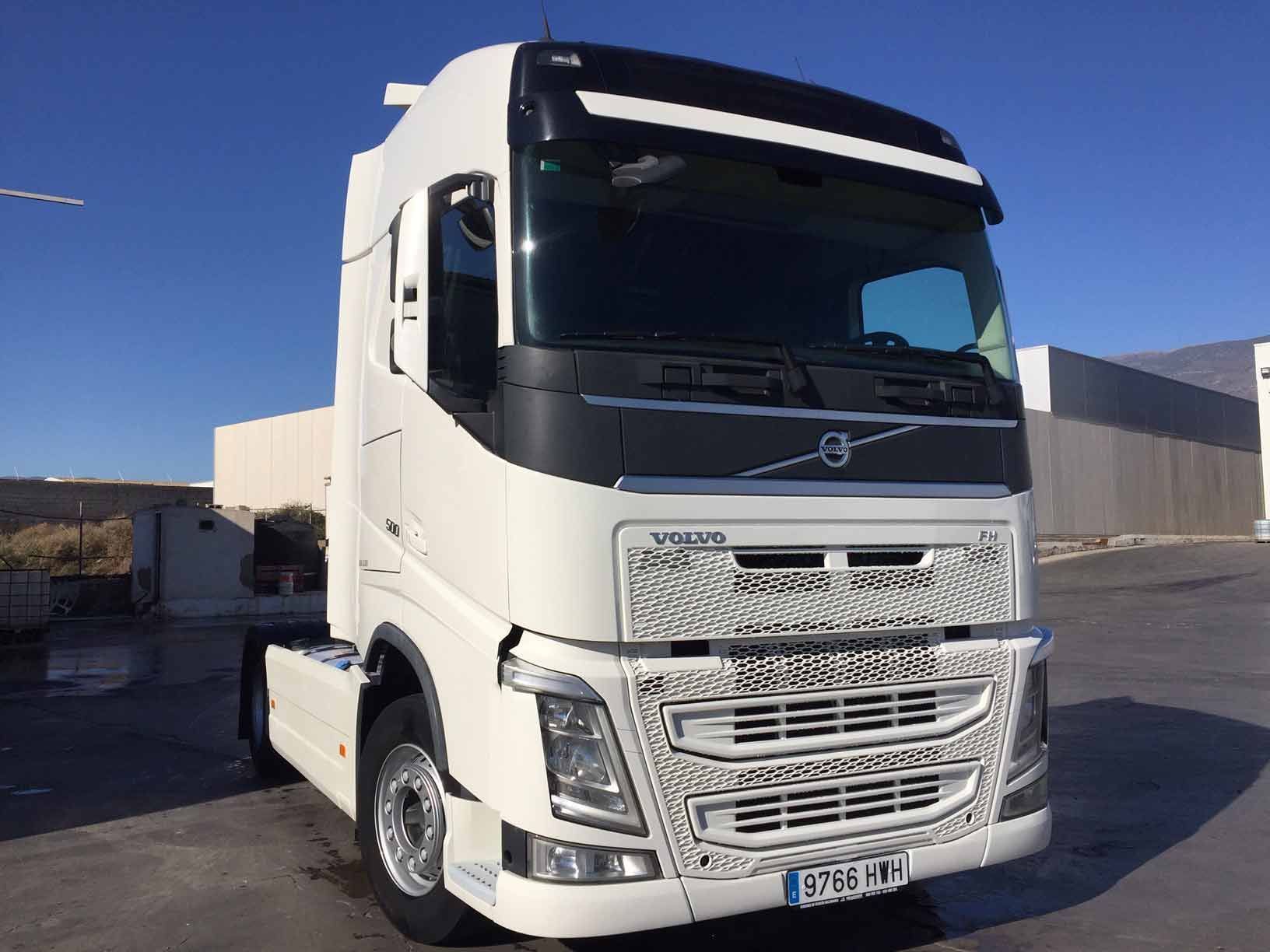 Un camión semirremolque blanco está estacionado en un estacionamiento.