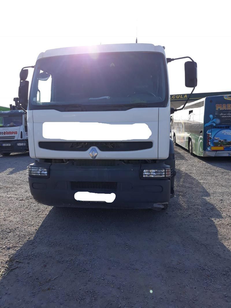 Un camión blanco está estacionado al lado de un autobús azul en un estacionamiento.