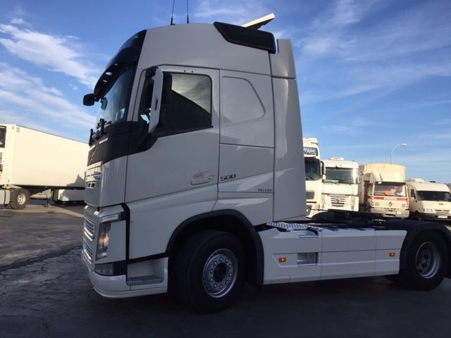 Un camión semirremolque blanco está estacionado en un estacionamiento.