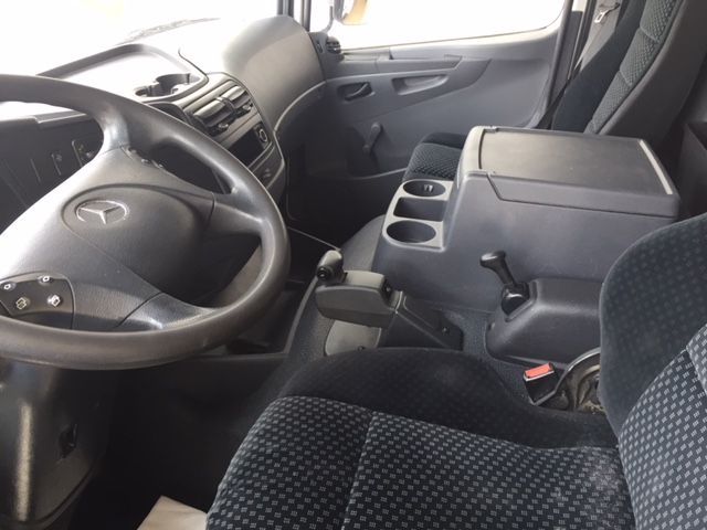 El interior de un camión con el logo de Mercedes en el volante.