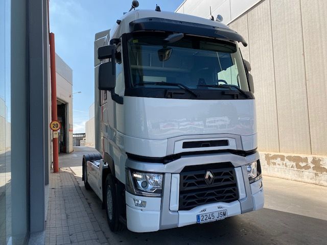 Un camión semirremolque blanco está estacionado frente a un edificio.