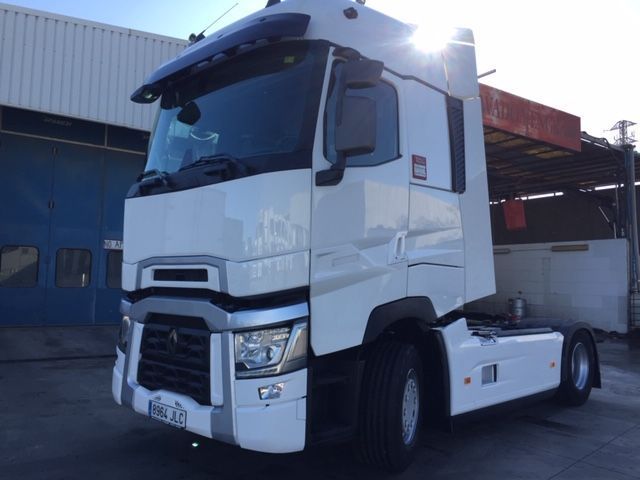 Un camión semirremolque blanco está estacionado frente a un edificio.