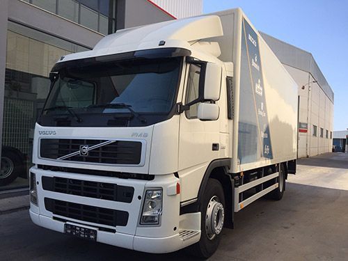 Un camión Volvo blanco está estacionado frente a un edificio.