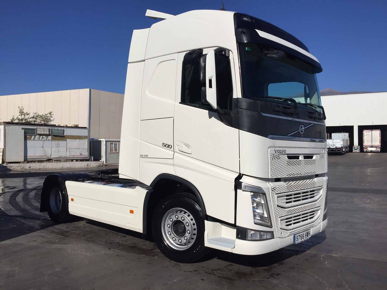 Un camión semirremolque blanco está estacionado en un estacionamiento.