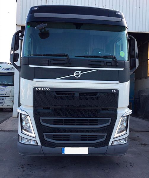 Un camión Volvo blanco está estacionado frente a un edificio.