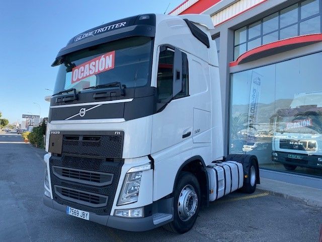 Un camión semirremolque Volvo blanco está estacionado frente a un edificio.