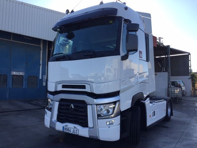 Un camión semirremolque blanco está estacionado frente a un edificio.