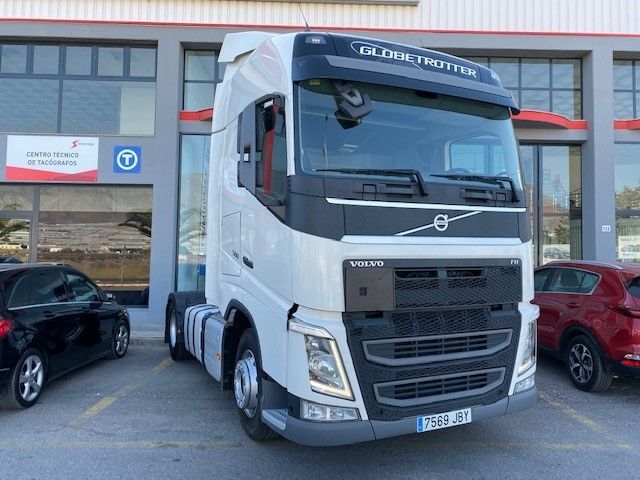 Un camión Volvo blanco está estacionado frente a un edificio.