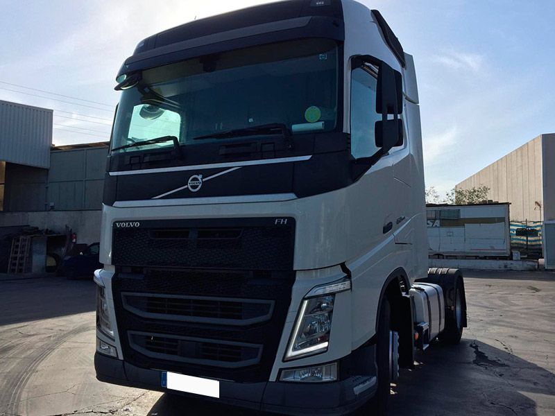 Un camión semirremolque Volvo blanco está estacionado en un estacionamiento.