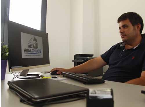 Un hombre está sentado en un escritorio frente a una computadora.