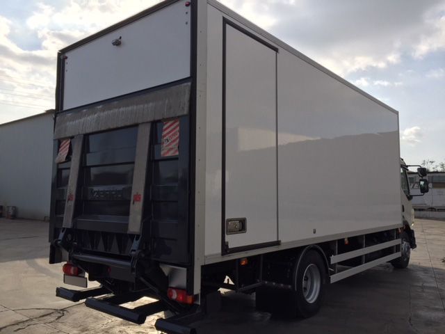 Un camión blanco con un elevador en la parte trasera está estacionado en un estacionamiento.