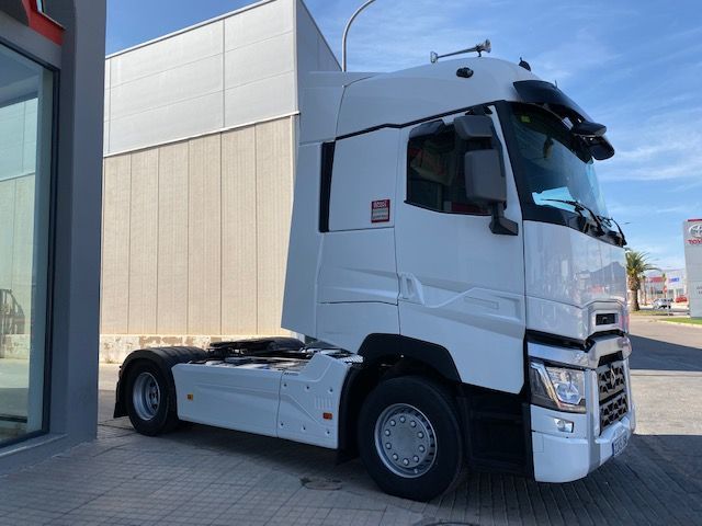 Un camión semirremolque blanco está estacionado frente a un edificio.
