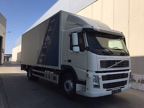 Un camión Volvo blanco está estacionado frente a un edificio.