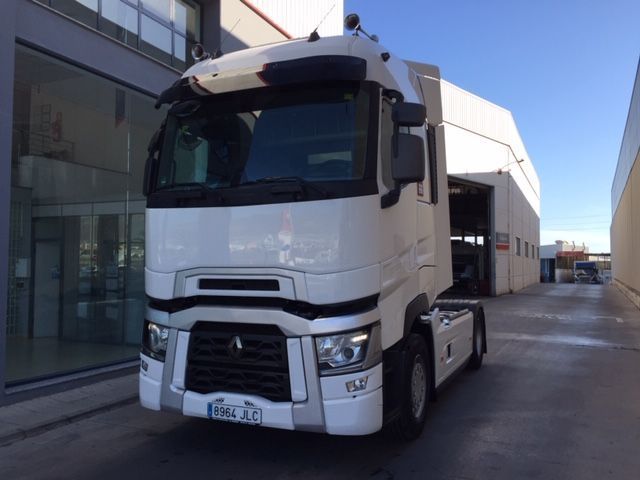 Un camión semirremolque blanco está estacionado frente a un edificio.