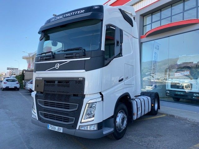 Un camión semirremolque Volvo blanco está estacionado frente a un edificio.