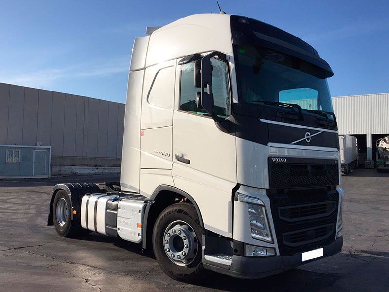 Un camión semirremolque blanco está estacionado frente a un edificio.