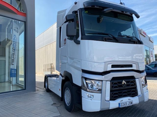 Un camión semirremolque blanco está estacionado frente a un edificio.