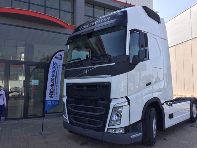 Un camión semirremolque Volvo blanco está estacionado frente a un edificio.