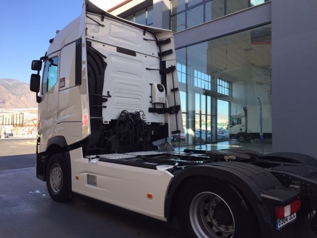 Un camión semirremolque blanco está estacionado frente a un edificio.