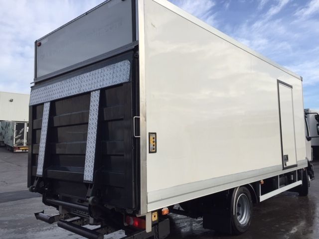 Un camión blanco con una puerta negra está estacionado en un estacionamiento.