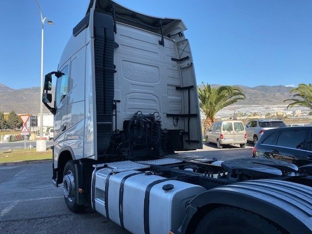 Un camión semirremolque está estacionado en un estacionamiento con montañas al fondo.