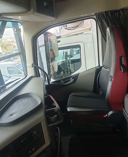 El interior de un camión con un asiento rojo y un asiento negro.