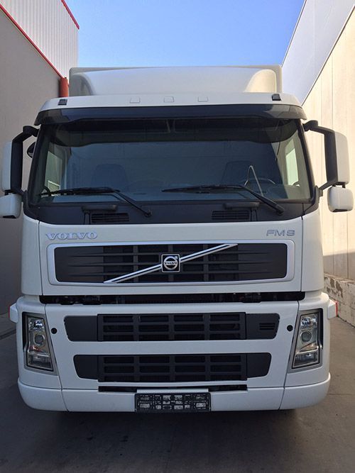 Un camión Volvo blanco está estacionado frente a un edificio.