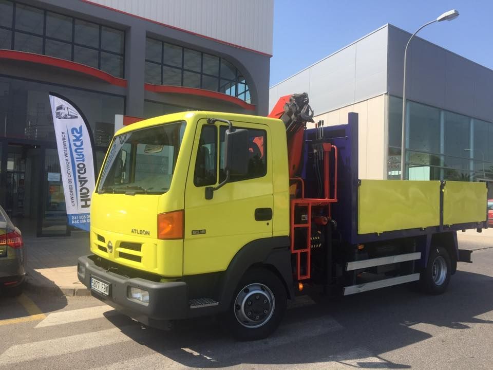 Un camión amarillo con una grúa en la parte trasera está estacionado frente a un edificio.