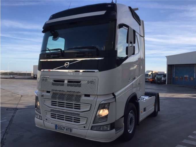 Un camión semirremolque Volvo blanco está estacionado en un estacionamiento.