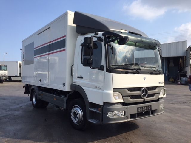 Una camioneta Mercedes blanca está estacionada en un estacionamiento.
